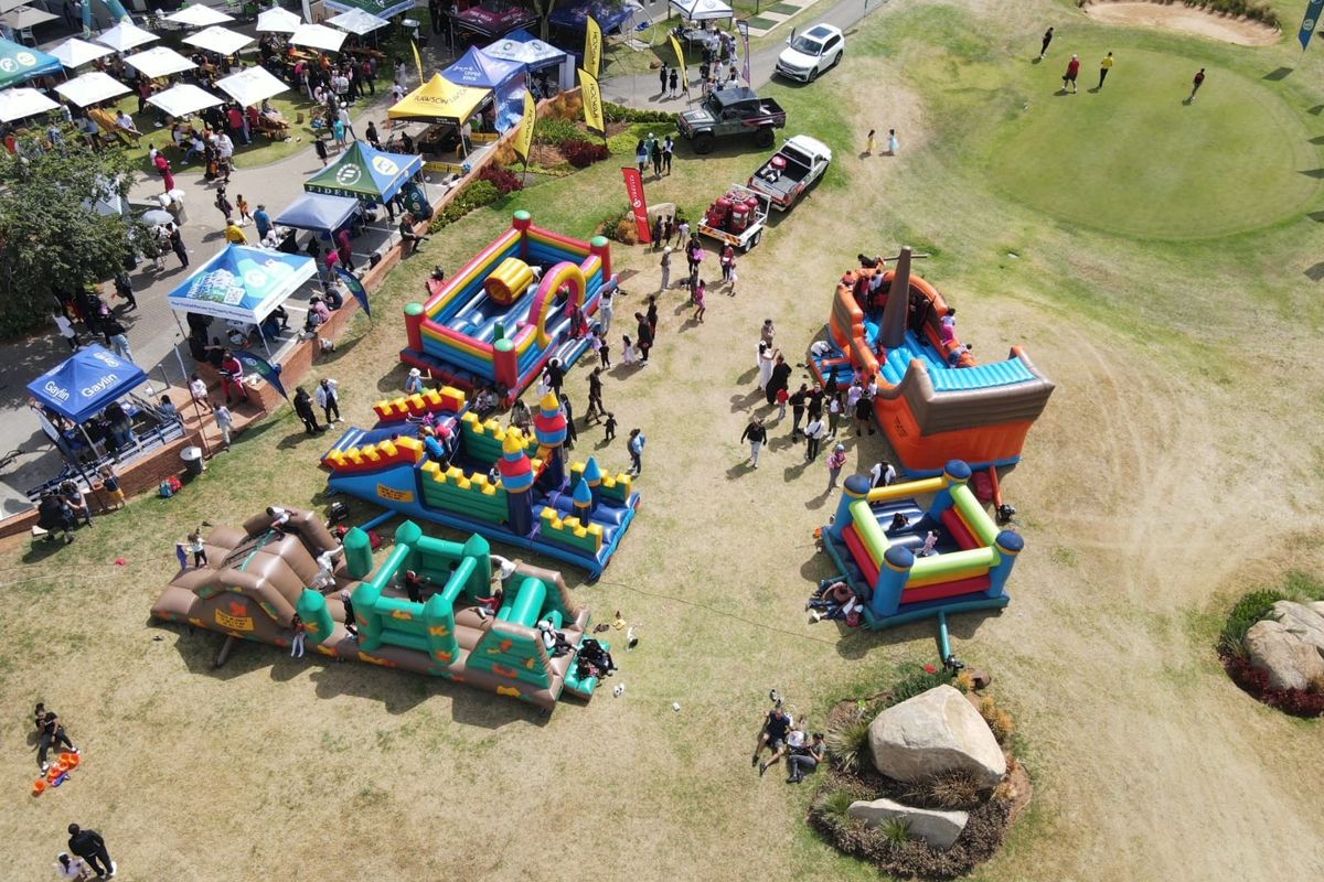 An aerial view of an outdoor event space featuring a large lawn area, golf course bunker, and various temporary event structures.