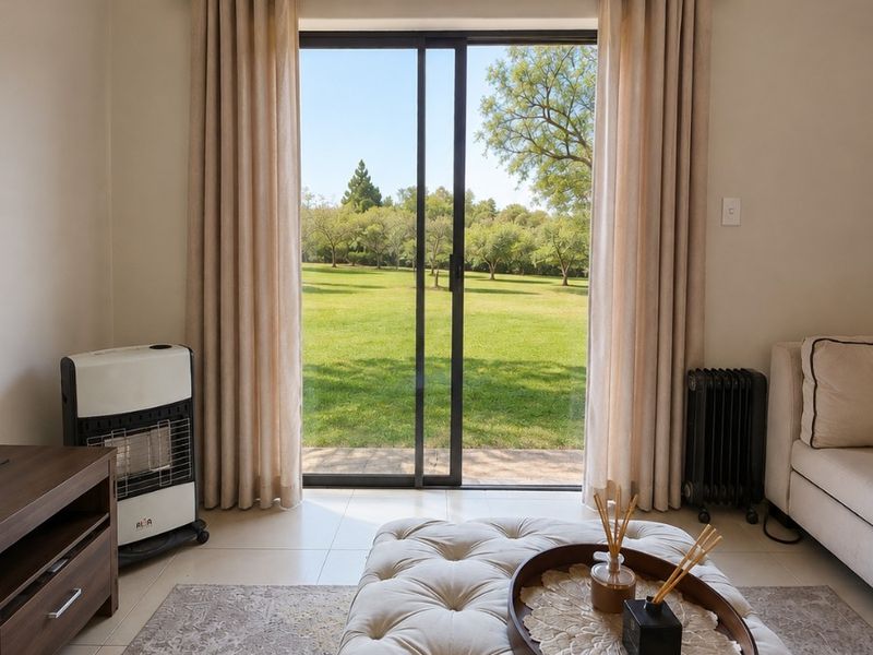 A bright living room featuring large sliding glass doors that provide direct access to a lush green garden view.