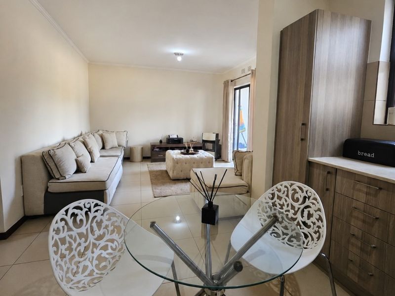 Open-plan living and dining area featuring neutral tiled flooring, built-in cabinetry, and access to an outdoor space via a sliding glass door.