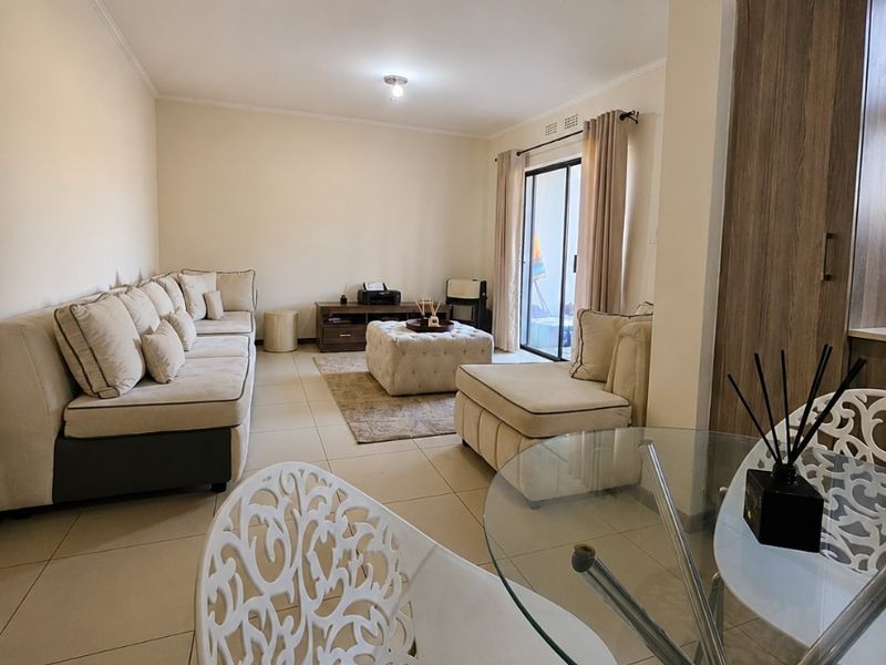 Open plan living and dining area featuring neutral tiled flooring, built-in cabinetry, and a sliding glass door providing access to the outdoor space.