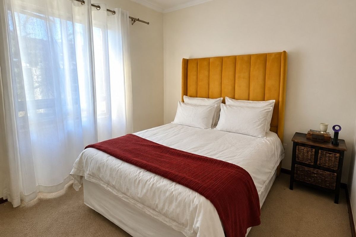 A well-maintained bedroom featuring neutral walls, carpeted flooring, and a ceiling-mounted spotlight fixture, offering a comfortable and functional living space.