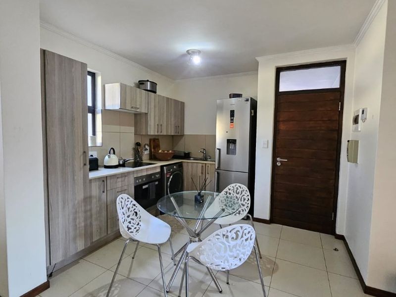 Open-plan kitchen and dining area featuring modern wood-look cabinetry, tiled flooring, and a functional layout with integrated appliances.
