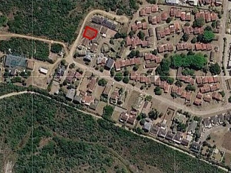 An aerial view of a residential neighborhood highlighting a specific vacant land plot outlined in red.