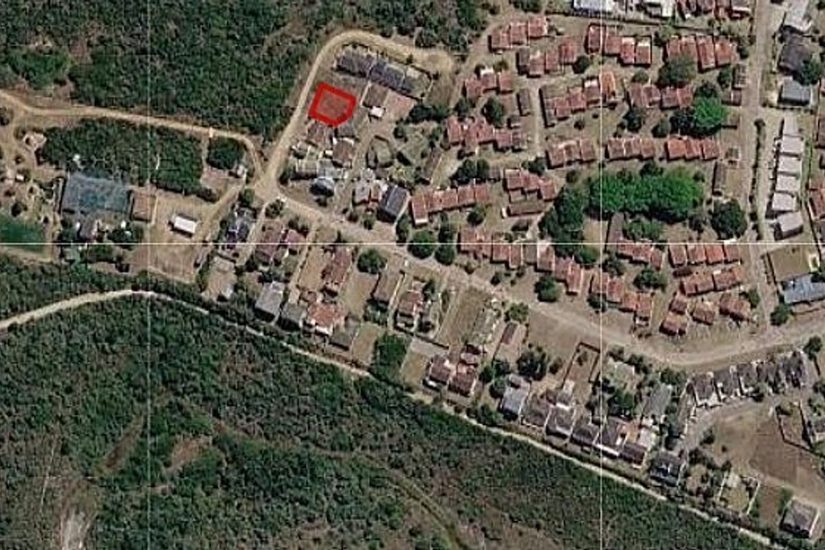 An aerial view of a residential neighborhood highlighting a specific vacant land plot outlined in red.