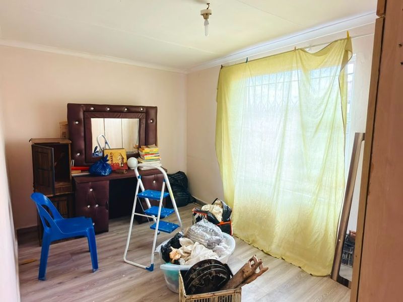 A bedroom featuring laminate flooring and a window fitted with a security gate, offering a blank canvas for potential interior updates.