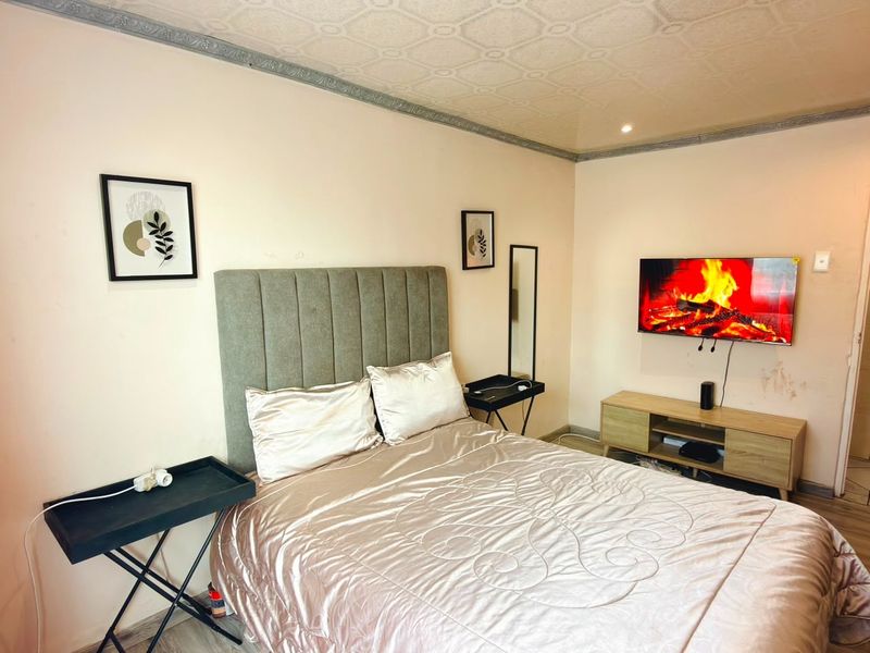 A bedroom featuring a textured ceiling with crown molding. The walls show signs of wear and staining, suggesting a need for cosmetic updates.