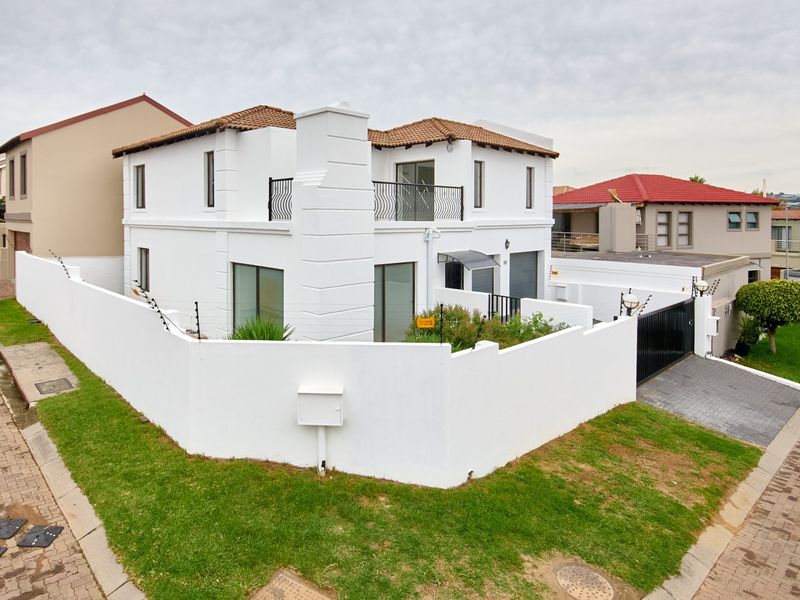 A modern two-story residential property featuring a white facade, terracotta roof tiles, a private balcony, and a secure perimeter wall with electric fencing.