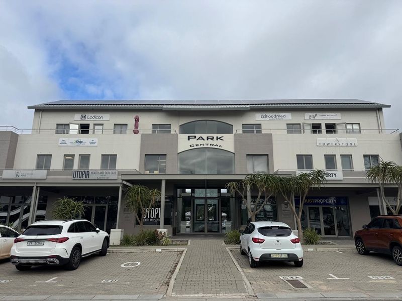Front elevation of Park Central office building featuring a paved parking area, modern glass entrance, and multiple commercial office units with balcony access.