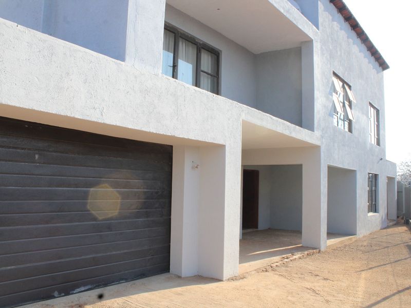 Front elevation of a multi-story house featuring a garage, covered entrance, and upper-level balcony with a textured exterior finish.