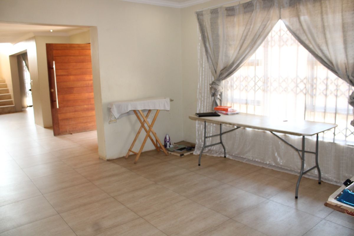 A spacious living area featuring neutral tiled flooring, coving, and a secure entrance, offering a blank canvas for interior design.