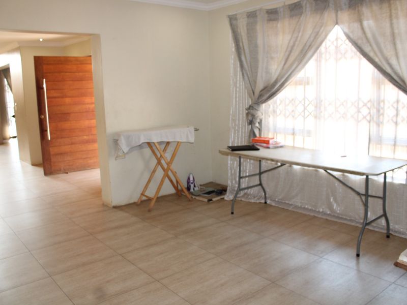 A spacious living area featuring neutral tiled flooring, coving, and a secure entrance, offering a blank canvas for interior design.