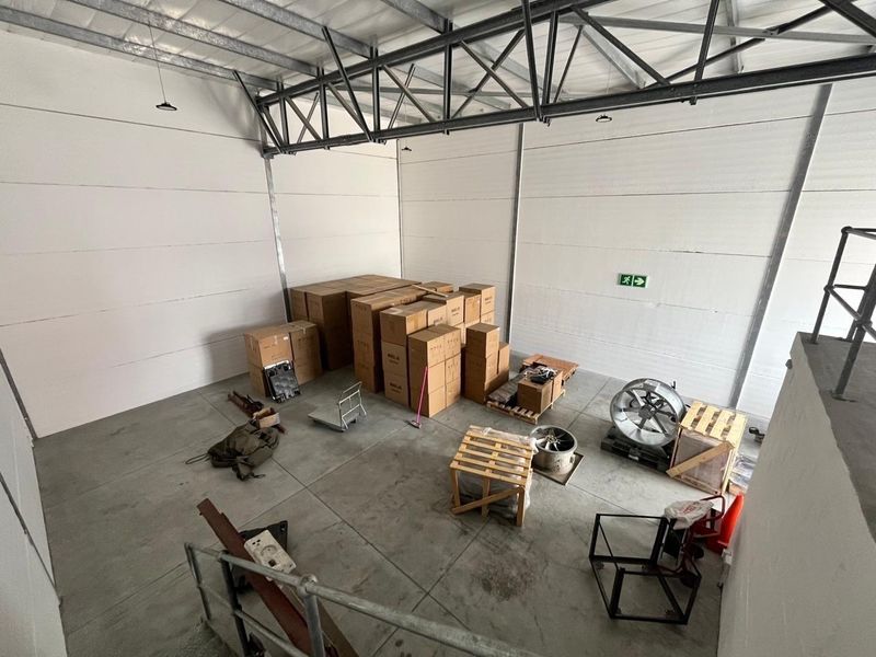 Spacious industrial utility area featuring high ceilings with exposed steel trusses, insulated wall panels, and durable concrete flooring, suitable for storage or workshop use.