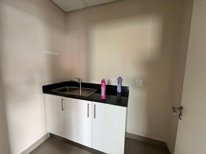A functional laundry or utility area featuring a stainless steel sink, granite countertop, and clean white built-in cabinetry.