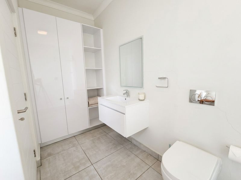 Modern bathroom featuring a wall-mounted vanity, built-in storage cabinetry, and a wall-mounted toilet with a sleek flush plate.