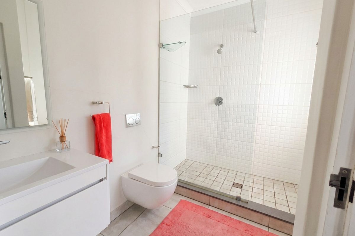Modern bathroom featuring a wall-mounted toilet, a sleek vanity with integrated sink, and a spacious walk-in shower with a glass screen.