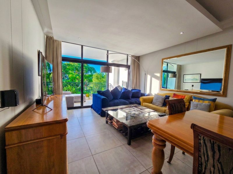 Spacious living room featuring large sliding glass doors leading to a balcony, tiled flooring, and recessed ceiling lighting.