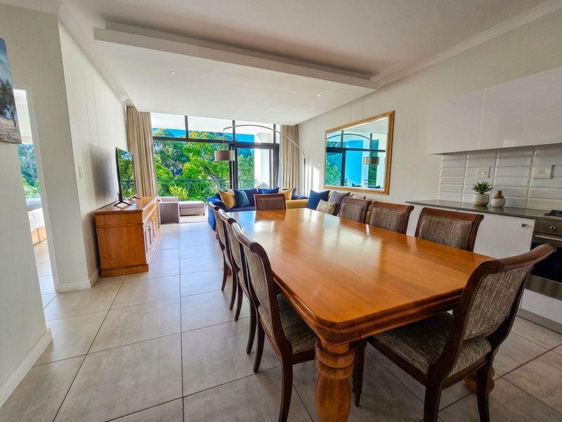 Spacious open-plan living and dining area featuring tiled floors, a modern kitchen with built-in appliances, and large sliding doors leading to a balcony.