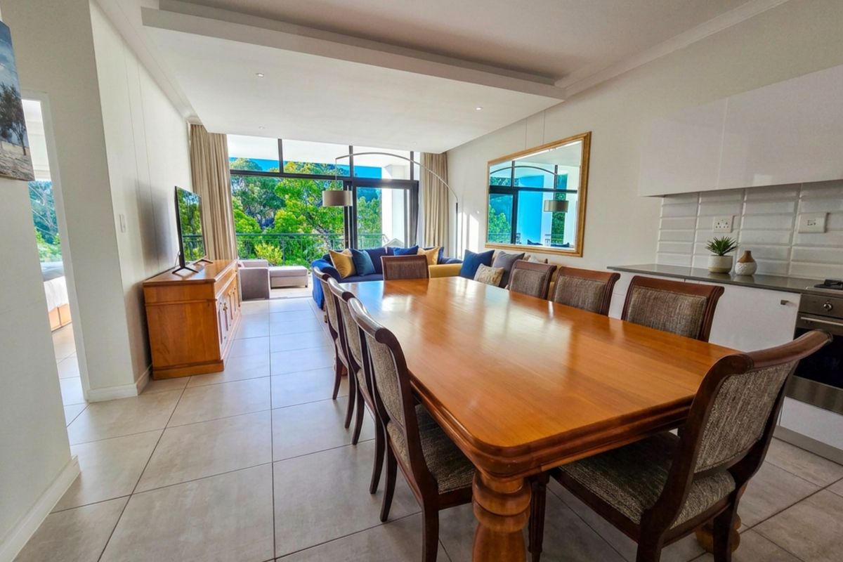 Spacious open-plan living and dining area featuring tiled floors, a modern kitchen with built-in appliances, and large sliding doors leading to a balcony.