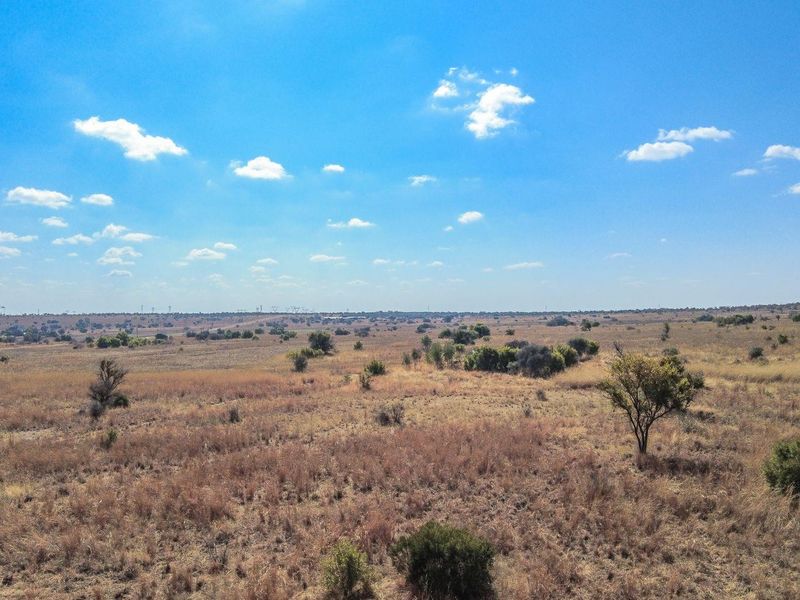 An aerial view of a large, undeveloped residential land plot featuring natural vegetation and open terrain.