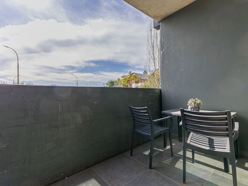A private balcony featuring tiled flooring and a painted brick wall, offering an open outdoor space for relaxation.