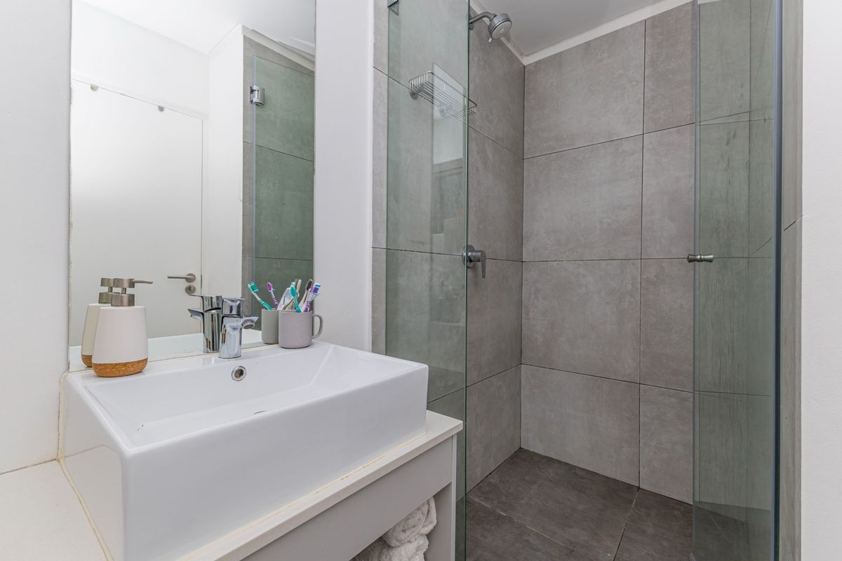 Modern bathroom featuring a vessel sink vanity, large wall mirror, and a spacious walk-in shower with grey tiled finishes and a glass screen.