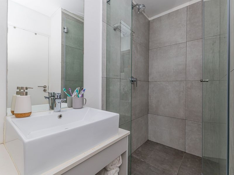 Modern bathroom featuring a vessel sink vanity, large wall mirror, and a spacious walk-in shower with grey tiled finishes and a glass screen.