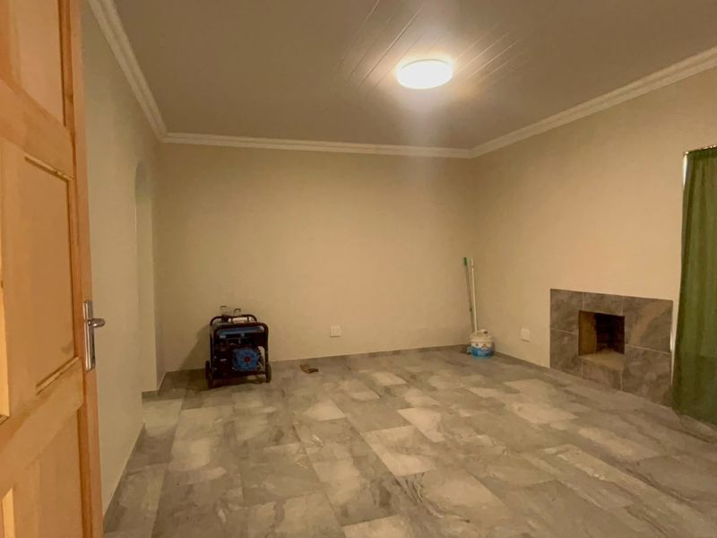 A spacious, empty living room featuring tiled flooring and a built-in fireplace, offering a neutral canvas for interior design.