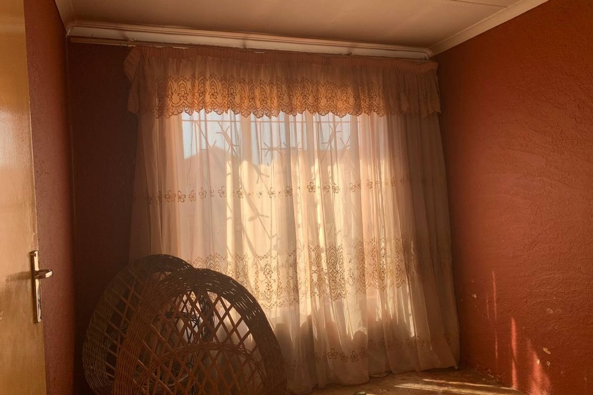 A bedroom featuring textured walls and a window with security bars, requiring cosmetic updates and repairs to the wall finishes.