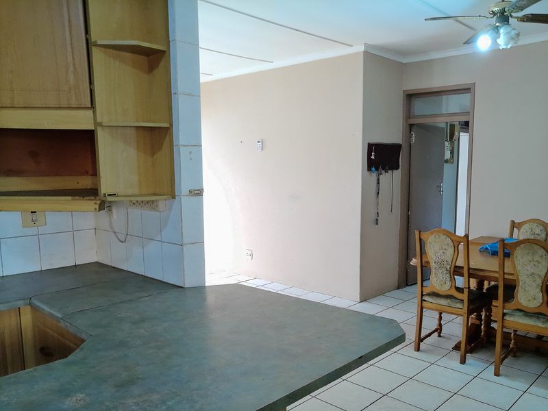 Open plan kitchen and dining area featuring tiled flooring, built-in cabinetry, and a breakfast counter, offering potential for modern renovation.
