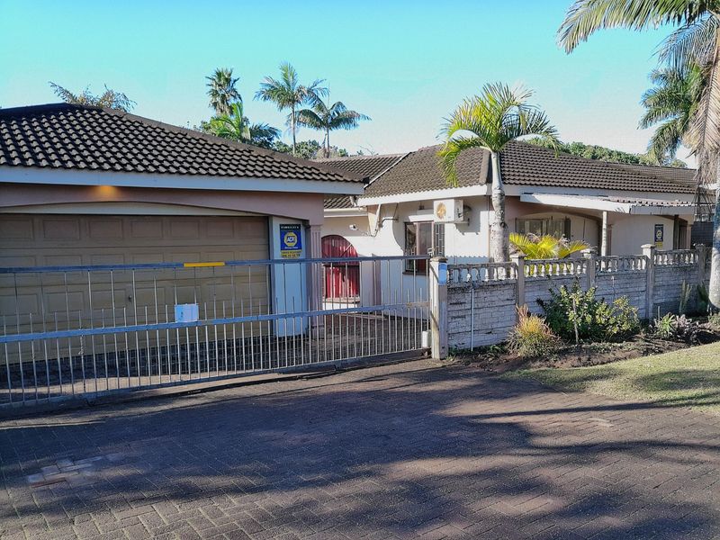 Front elevation of a single-story house featuring a tiled roof, attached garage, secure sliding gate, and a paved driveway.