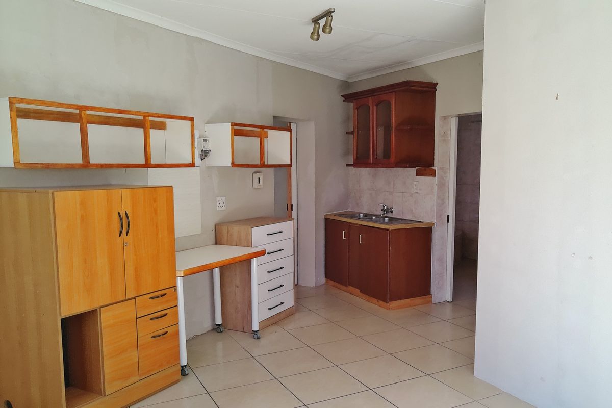 A functional kitchen space featuring tiled flooring, built-in cabinetry, and a stainless steel sink, currently awaiting cosmetic updates and finishing touches.