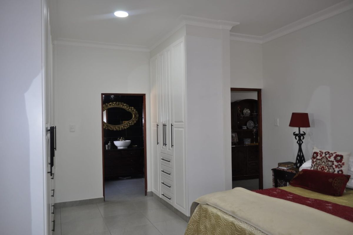 A well-maintained bedroom featuring extensive built-in cabinetry, neutral tiled flooring, and direct access to an adjoining bathroom.
