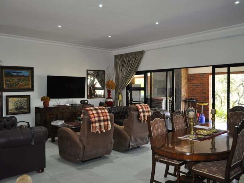 Spacious open-plan living and dining area featuring tiled flooring, recessed downlights, and large sliding glass doors providing access to the outdoor patio.
