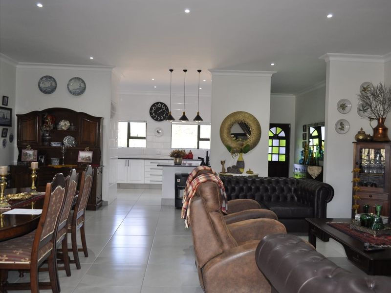 Spacious open-plan living and dining area featuring tiled floors, recessed lighting, and a modern kitchen with a central island.