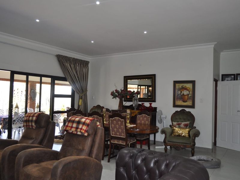 Spacious open-plan living and dining area featuring tiled flooring, recessed downlights, and large sliding glass doors providing access to the outdoor patio.