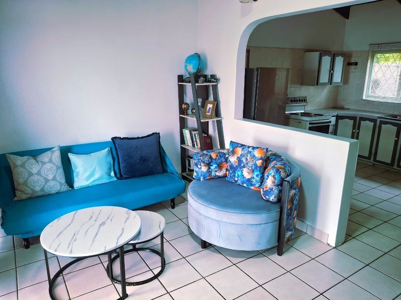 Open plan living area featuring tiled flooring and an arched pass-through to the kitchen, which includes built-in cabinetry and a stove.