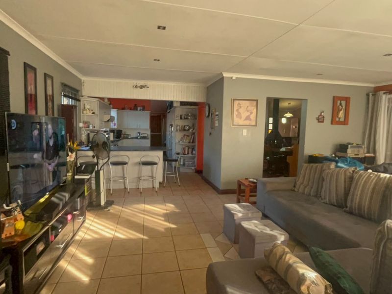 Open-plan living area featuring tiled flooring, recessed lighting, and a breakfast bar connecting to the kitchen space.