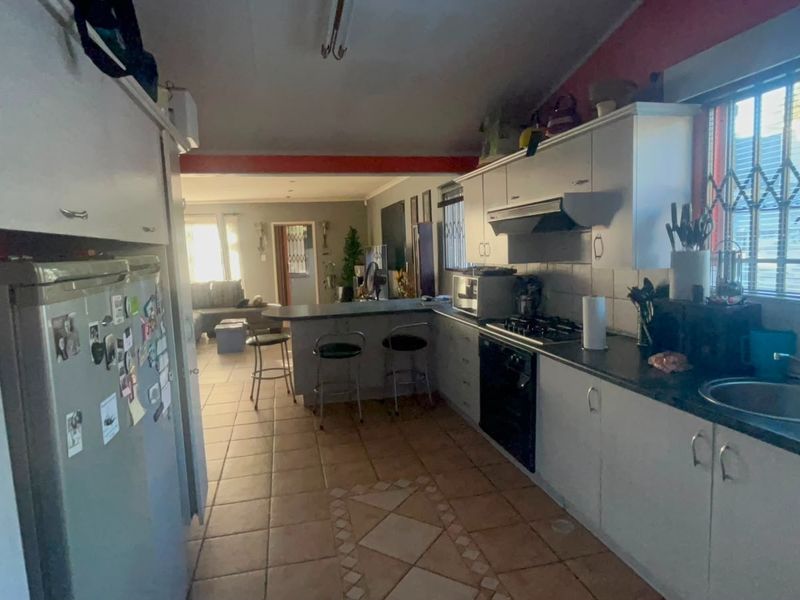 Open-plan kitchen and living area featuring tiled flooring, built-in cabinetry, a breakfast counter, and a gas hob with an extractor fan.