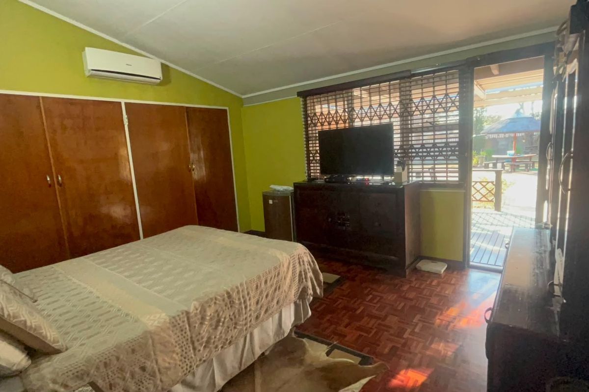 Bedroom featuring parquet flooring, built-in cupboards, and a split-system air conditioner, with direct access to an outdoor patio area.