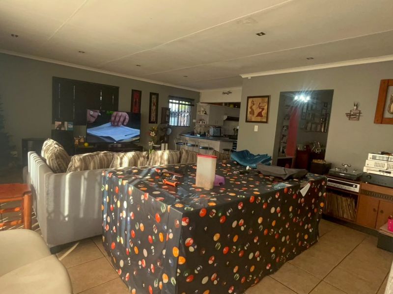 Spacious open-plan living area featuring tiled flooring and recessed downlights, seamlessly connecting to the kitchen space.