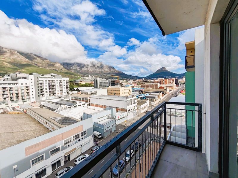 A balcony featuring a metal balustrade and tiled flooring, offering expansive urban and mountain views.