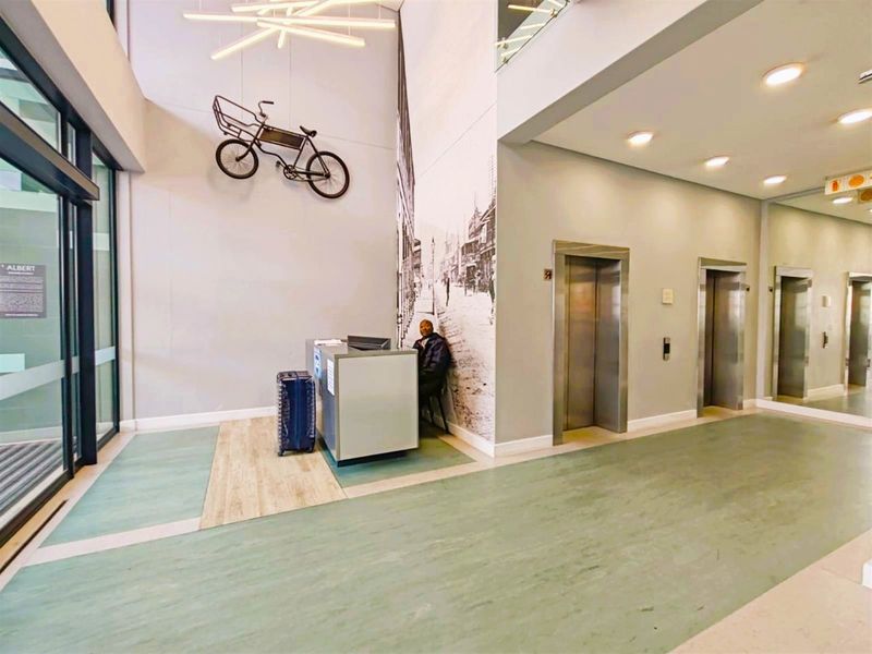 Modern apartment building entrance lobby featuring a reception desk, multiple elevators, and contemporary finishes.