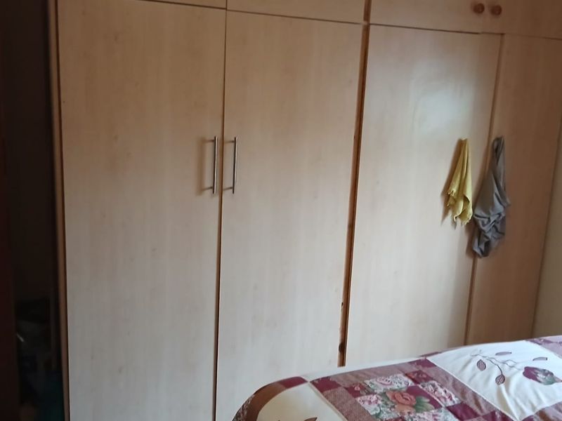 A bedroom featuring floor-to-ceiling built-in wooden cupboards providing ample storage space.