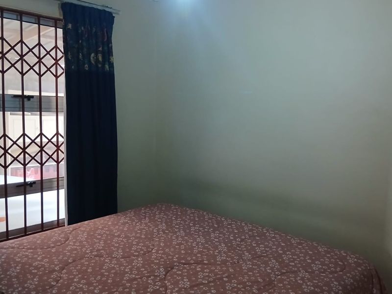 A simple bedroom featuring a security gate on the window and basic cove cornicing.