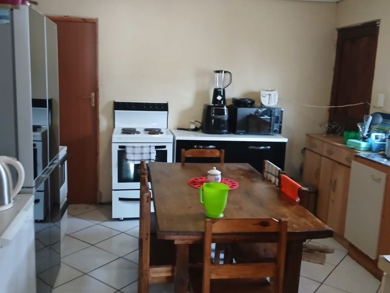 A functional kitchen featuring tiled flooring, freestanding stove, and built-in cabinetry, offering potential for modernization and layout optimization.