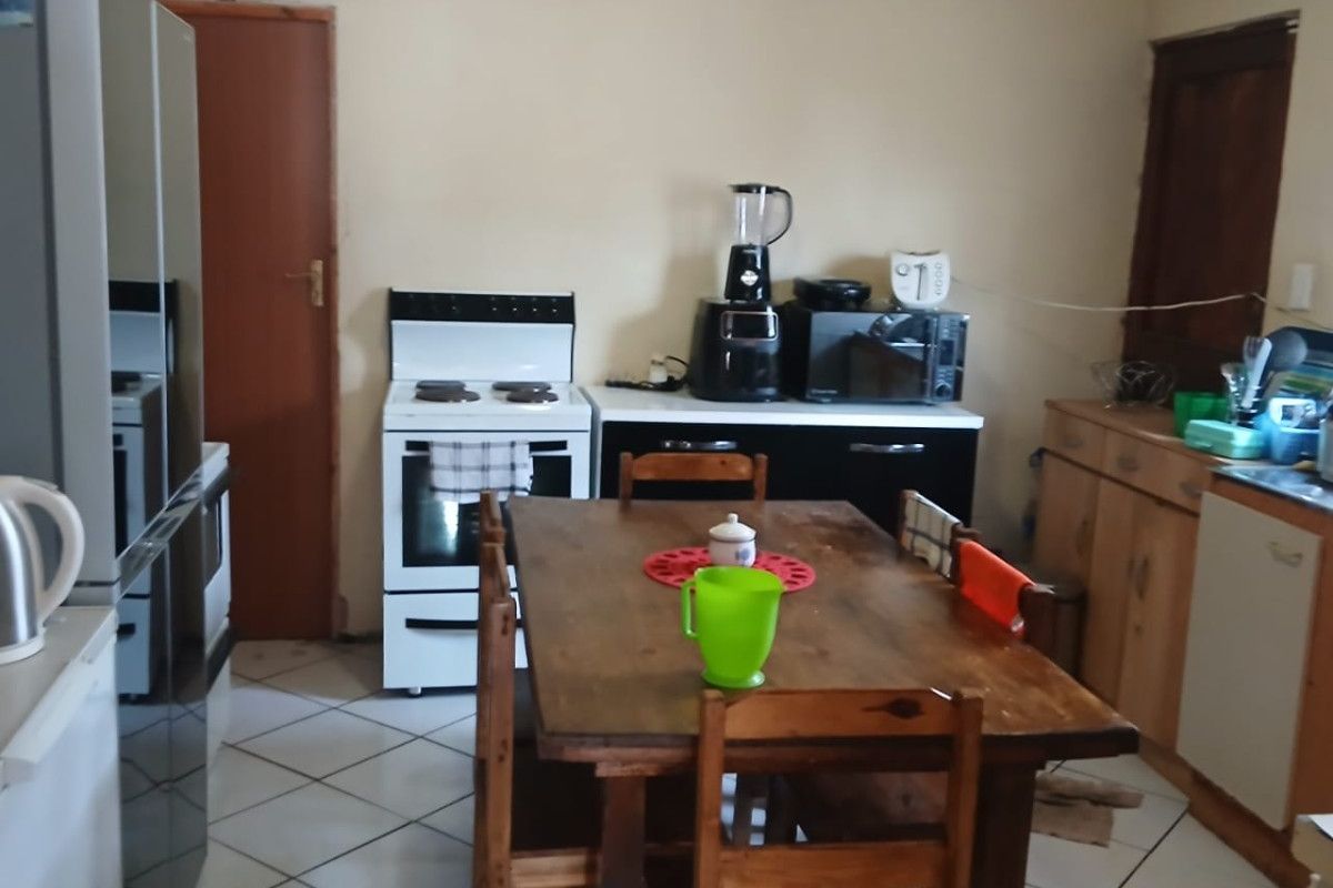 A functional kitchen featuring tiled flooring, freestanding stove, and built-in cabinetry, offering potential for modernization and layout optimization.