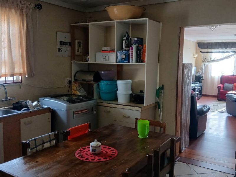 A functional kitchen area featuring tiled flooring, built-in cabinetry, and a stainless steel sink, with an open flow into the adjacent living space.