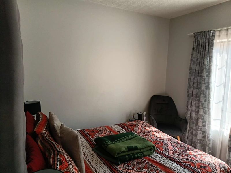 A standard bedroom featuring neutral walls and natural light through window curtains.