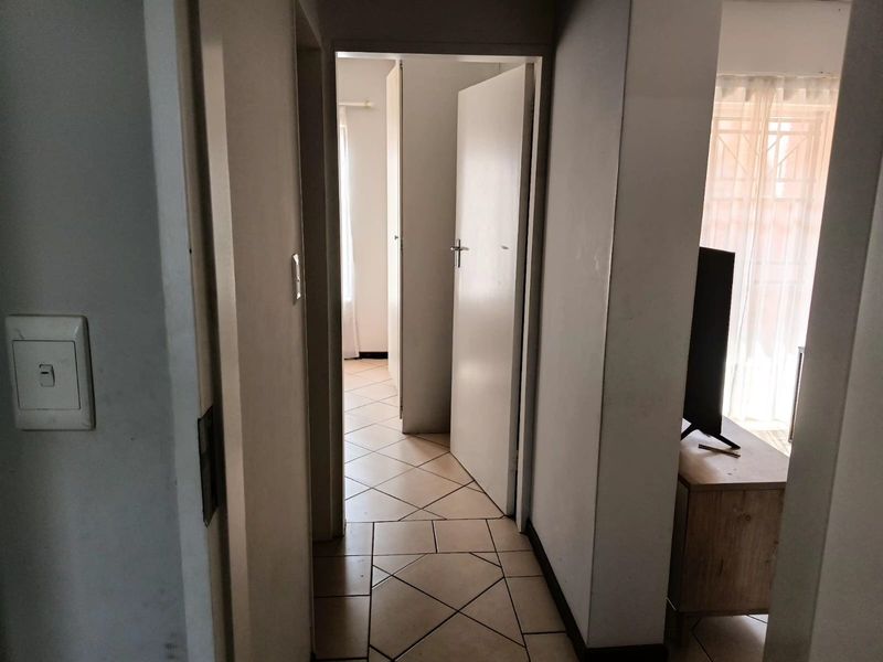 A functional hallway with tiled flooring connecting various rooms within the apartment, featuring neutral walls and standard internal door access.