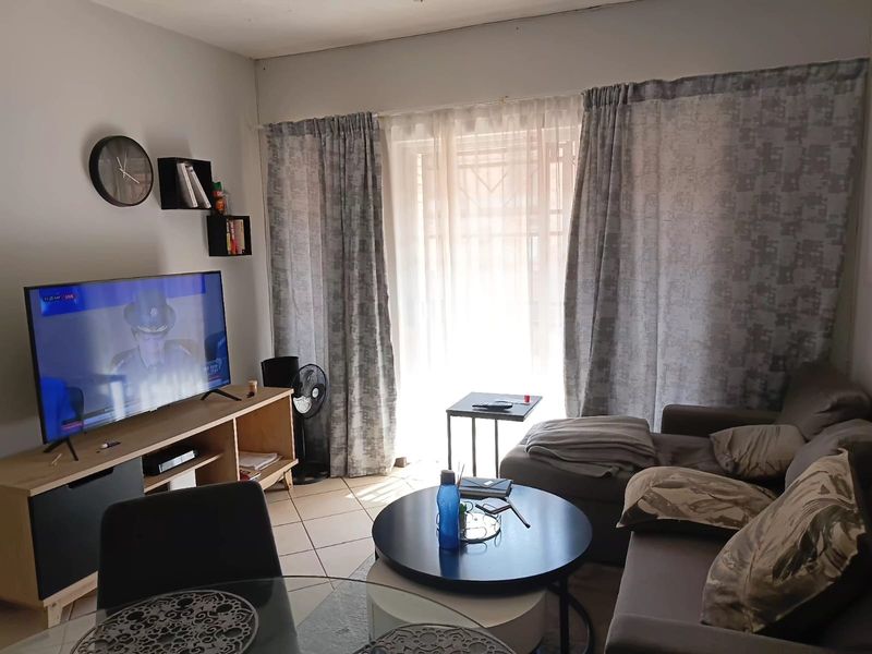 A functional living room featuring tiled flooring and a sliding glass door that provides natural light.